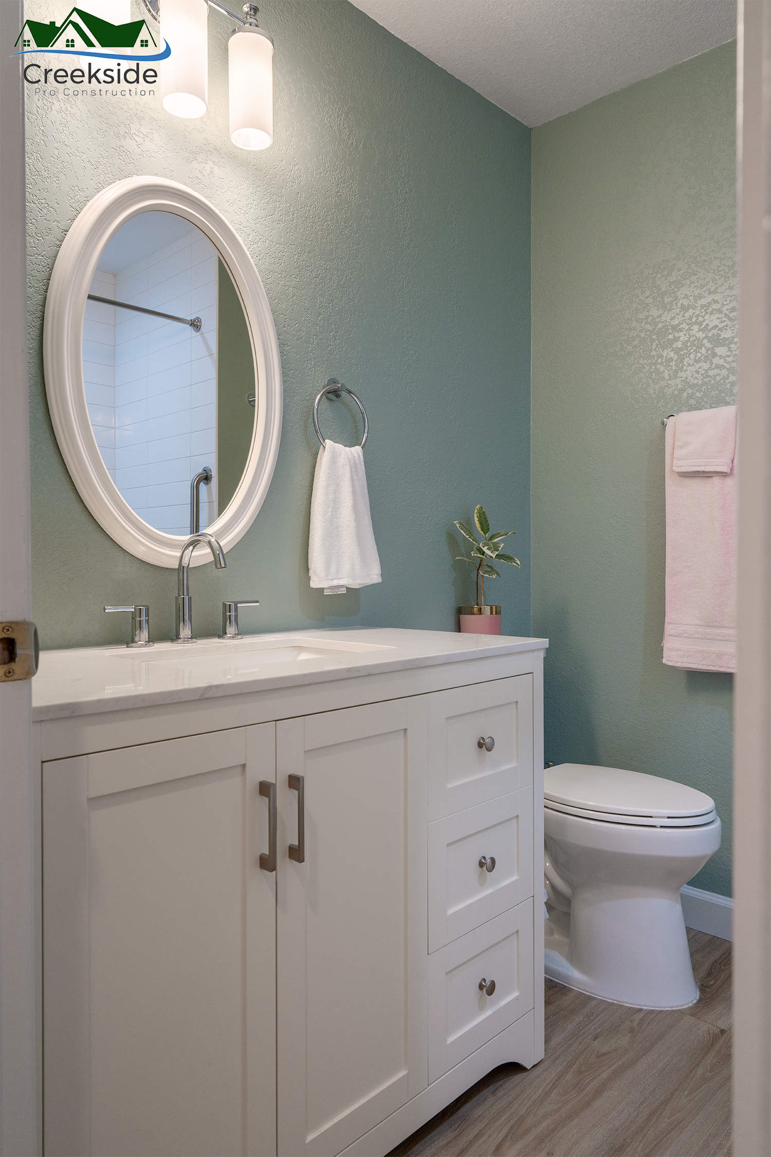 bathroom with white shaker vanity and seafoam green.