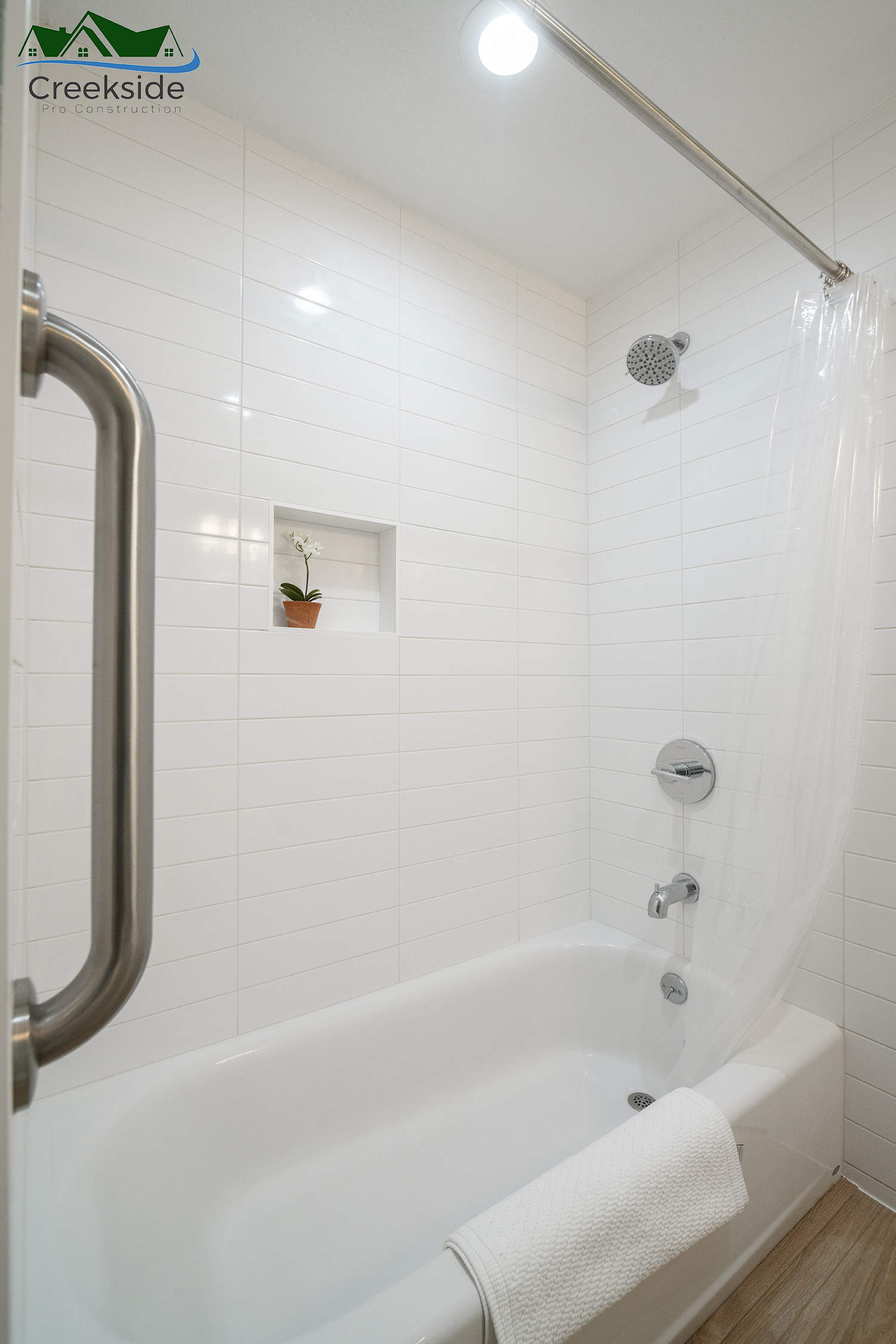 renovated bathroom shower with white tiles, and chrome finishes.