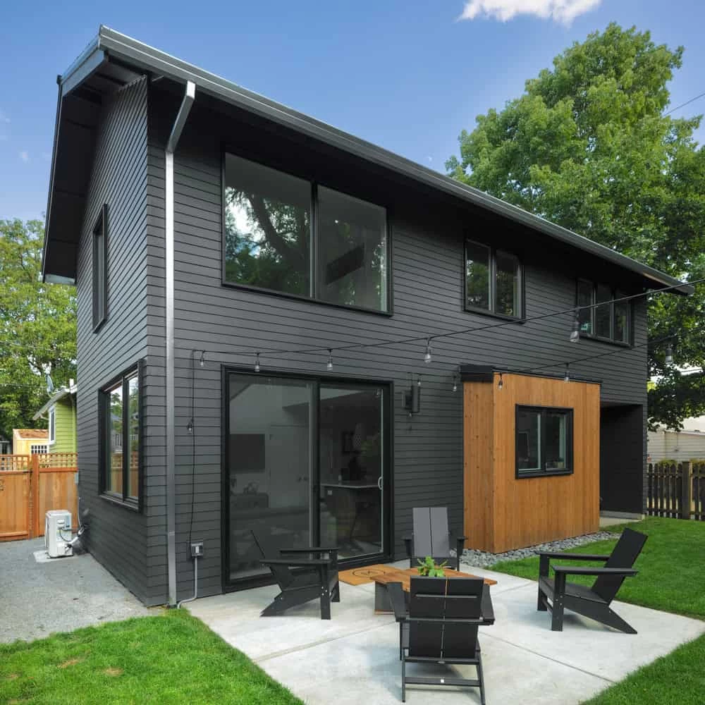 A modern two-story house with dark grey siding and large windows.
