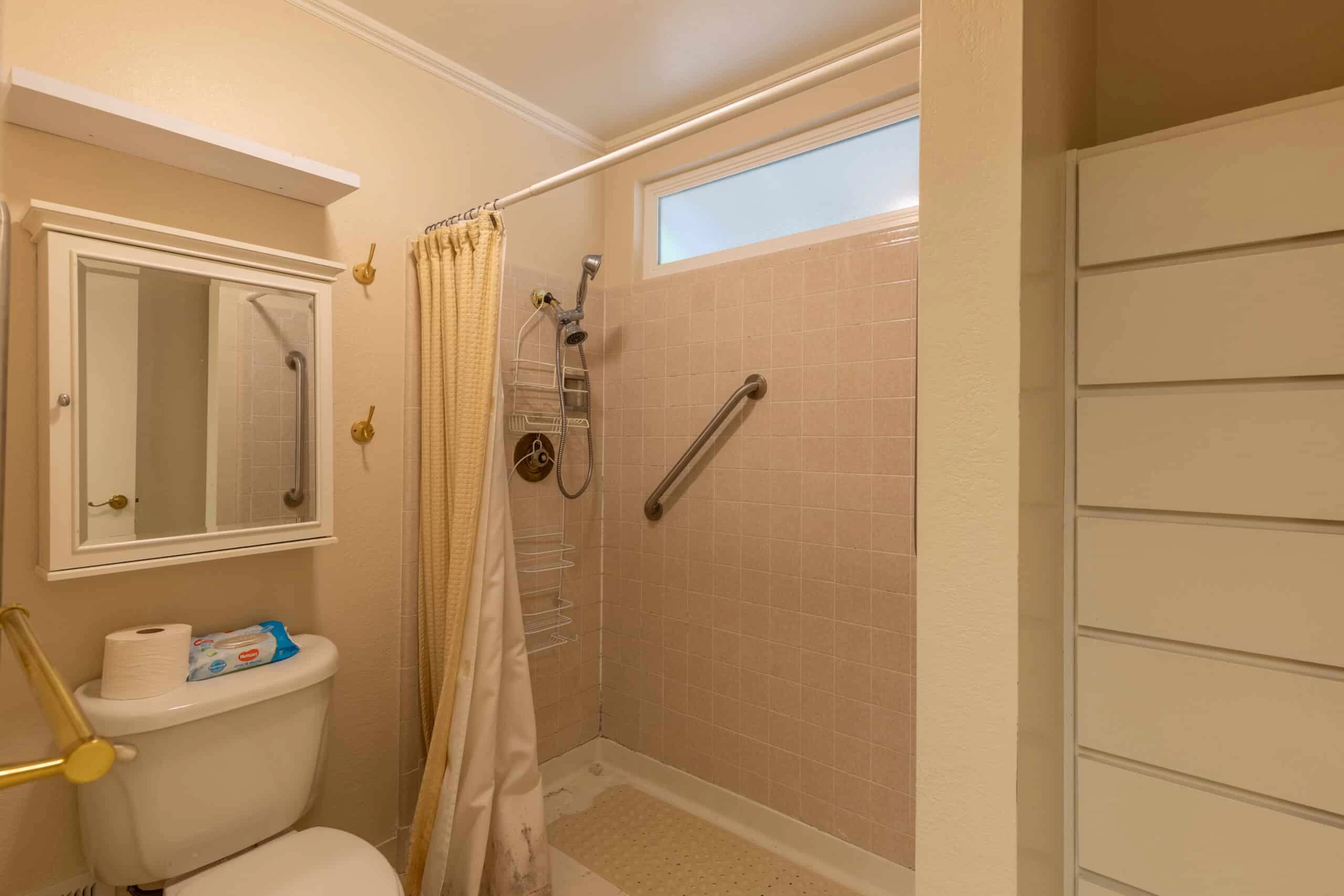 Bath Room Interior – Contra Costa County, CA Accessible bathroom with a walk-in shower featuring a grab bar, showerhead, and hanging caddy.