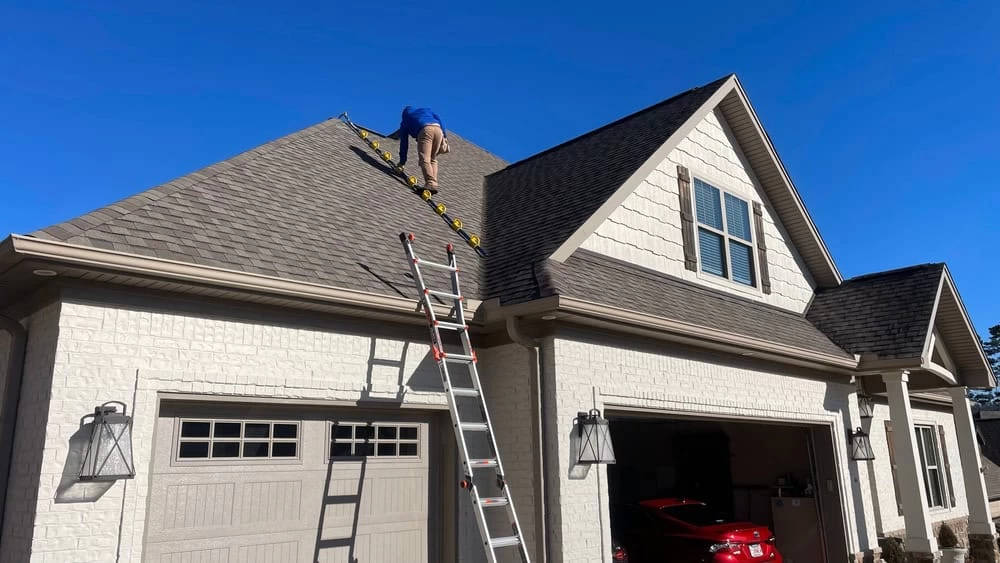 A man on a ladder cleaning the roof of a house in Contra Costa County, CA.